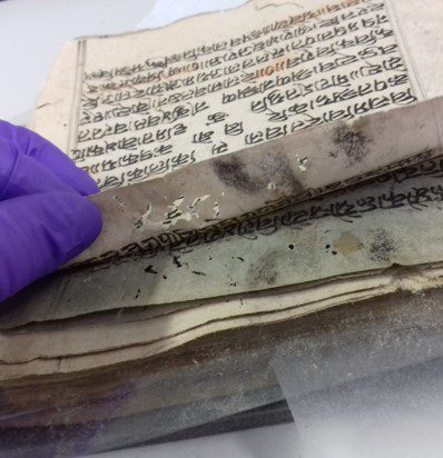 Historical manuscript with mould, insect damage and adhered pages.